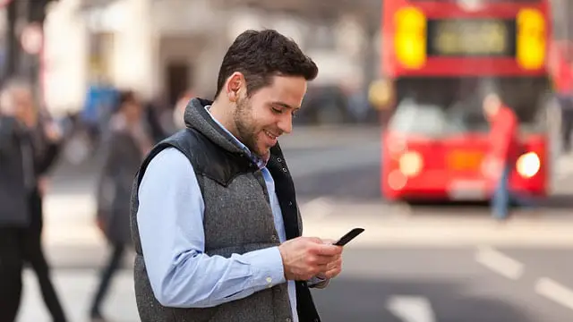 Homem usando celular em rua na Europa