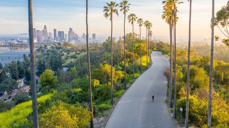 Drone shot of a woman walking down a street toward Downtown Los Angeles.