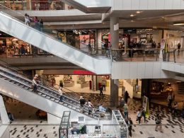 Interior de um Outlet com pessoas comprando em lojas