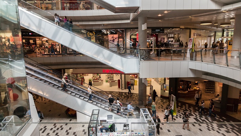 Interior de um Outlet com pessoas comprando em lojas