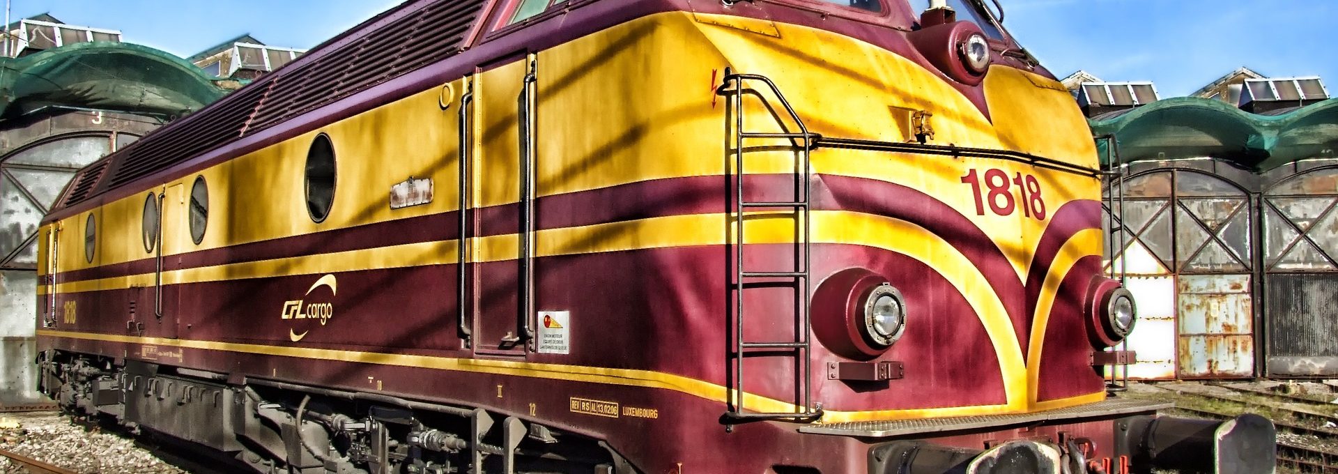 Comboio nas cores vermelho e amarelo numa estrada de ferro