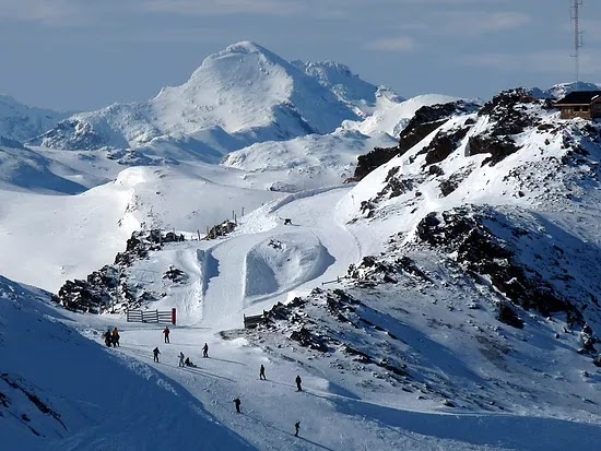 Pessoas andam em meio à neve e às montanhas cobertas com neve em Ushuaia