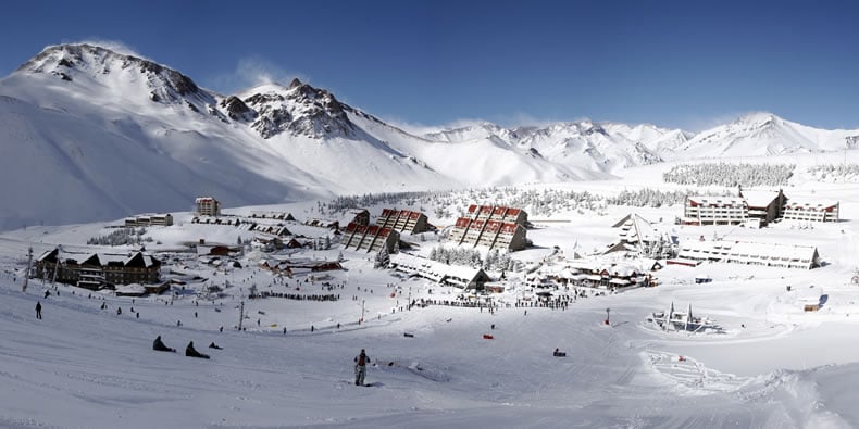 Vista da estação de esqui em Mendoza. Nota-se pessoas praticando o esporte em meio à neve
