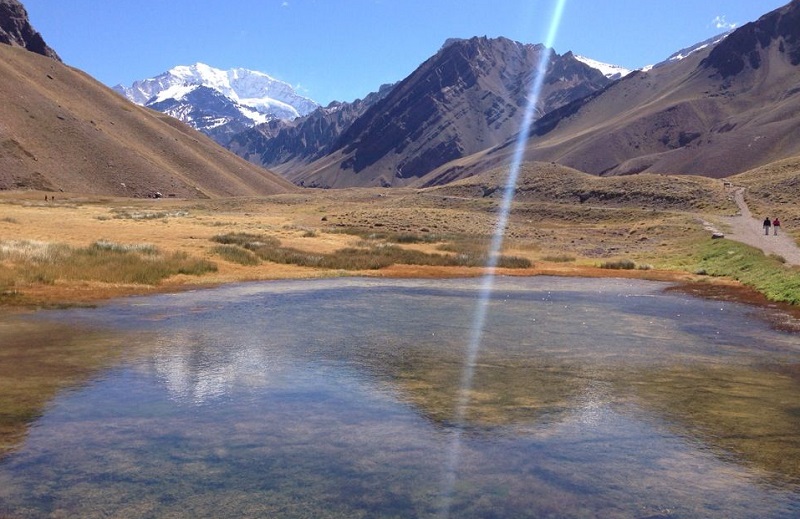 Vista do Parque Aconcágua em Mendoza. Nota-se um lago em primeiro plano com terra ao redor e montanhas ao fundo