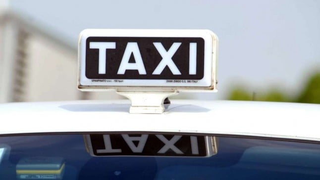 Placa indicando "Táxi" em cima de um carro