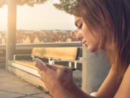 Mulher usa o celular em praça pública