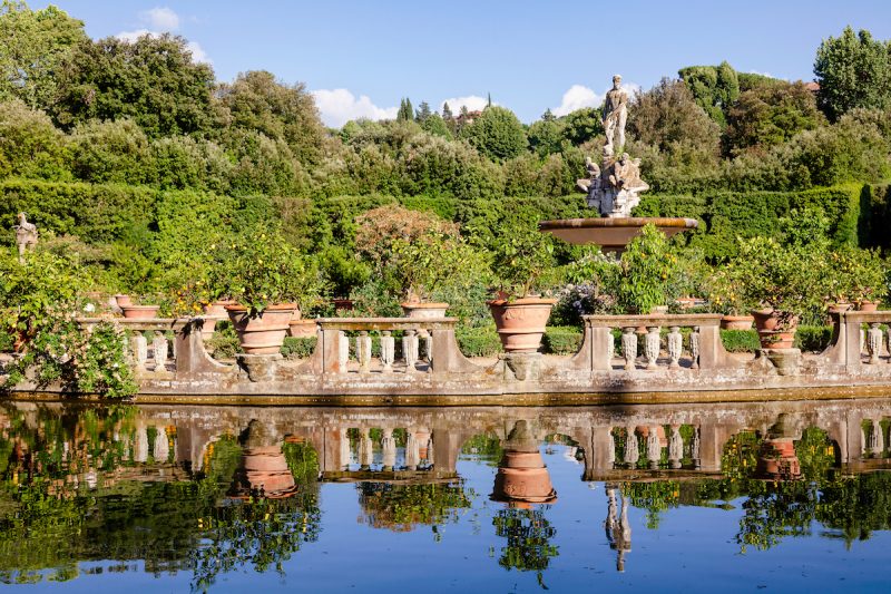 Vista de fonte com uma estátua no topo e um lago no Jardim de Bóboli.