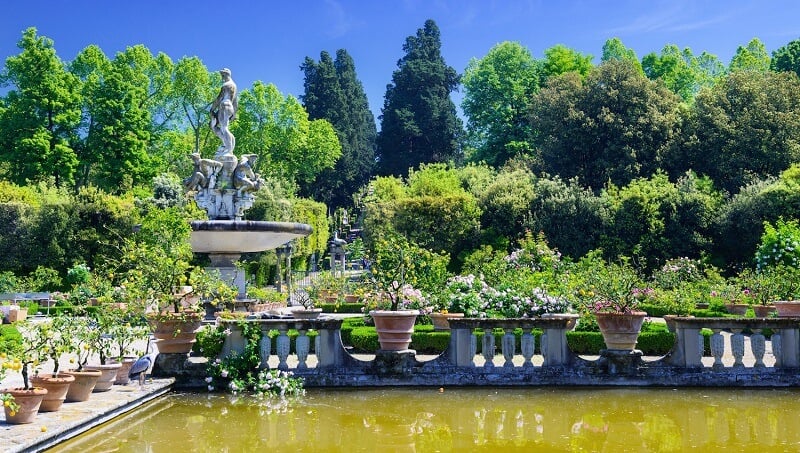 Jardim do Palazzo Pitti. Nota-se uma fonte com esculturas e um lago próximo à arbustos do lugar.