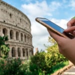 Usando o celular em frente ao Coliseu de Roma na Itália Usando o celular em frente ao Coliseu de Roma na Itália