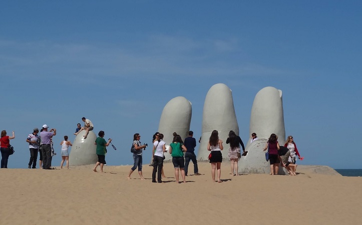 Turistas contemplando o Monumento Los Dedos em Punta del Este