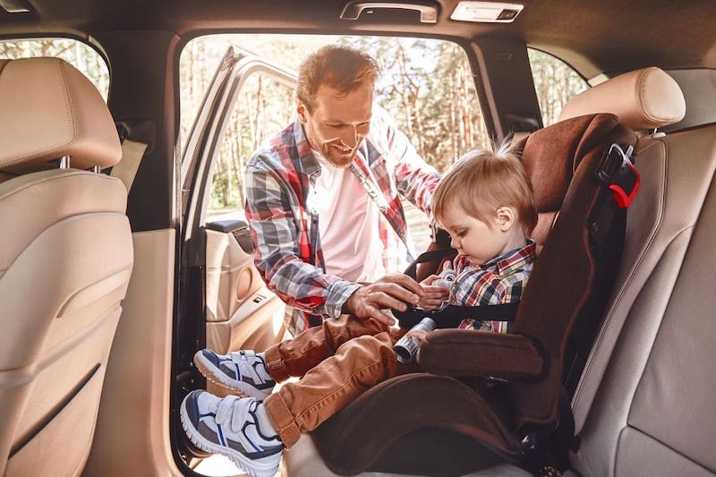 Pai colocando criança na cadeirinha de carro